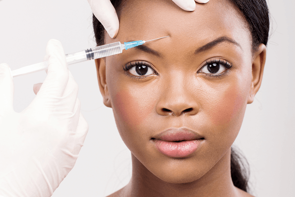 Attractive African-American woman with vibrant smooth skin getting an cosmetic injectable treatment on her forehead