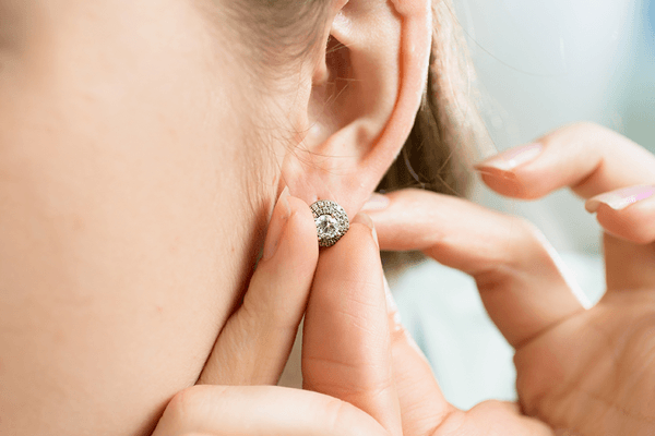 Closeup of a brunette woman putting on earrings