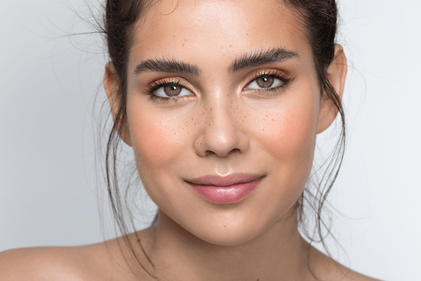 Closeup of a beautiful young brunette woman looking happy while gazing at the camera