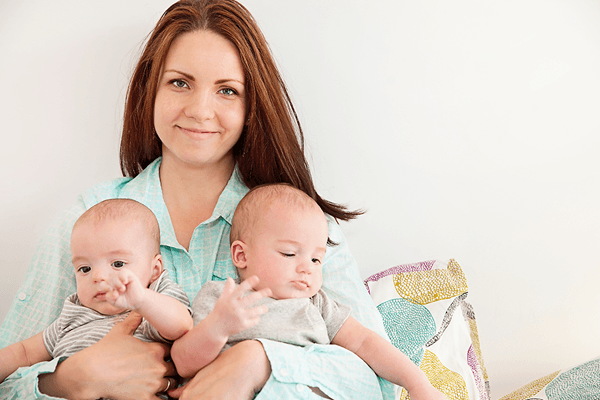 Mother holding her twin sons and smiling contentedly